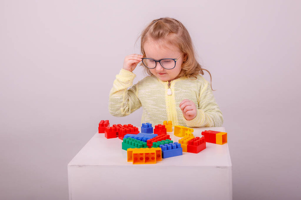 little cute blonde girl playing in a constructor on a white background. Concept of preschool education - 写真・画像