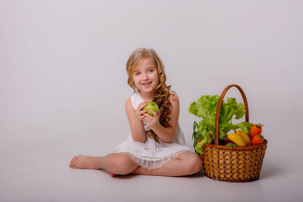スタジオで野菜のバスケットを持った少女の肖像画です - 写真・画像