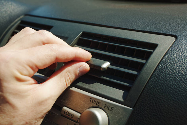 Zbliżenie kratek wentylatora lub klimatyzatora na panelu samochodowym. Ręka mężczyzny reguluje dopływ powietrza do wnętrza samochodu. - Zdjęcie, obraz