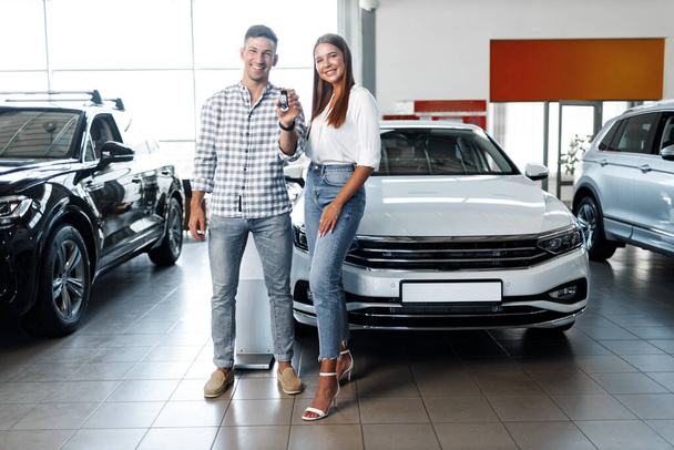 若い幸せなカップルはちょうど販売店で新しい車を買った - 写真・画像