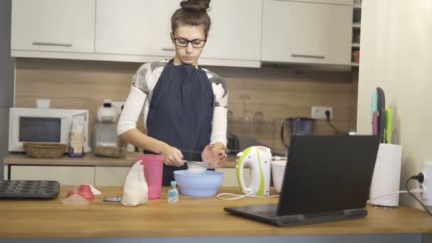 women with glass made muffins with recipes from laptop at home  - Footage, Video