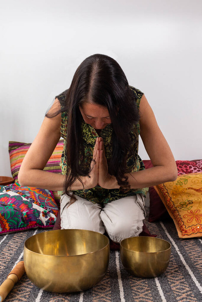 Μεσήλικη γυναίκα ετοιμάζεται να χρησιμοποιήσει τα θιβετιανά κύπελλα τραγουδιού. - Φωτογραφία, εικόνα