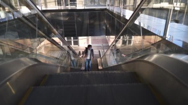 Καυκάσιος με προστατευτική μάσκα ανεβαίνει τις κυλιόμενες σκάλες σε άδειο αεροδρόμιο. Ταξίδι κατά τη διάρκεια επιδημίας του ιού Corona covid 19. Κρατήστε ασφαλή απόσταση. Άντρας με μάσκα πηγαίνει στην πύλη για ταξίδι με αεροπλάνο. - Πλάνα, βίντεο