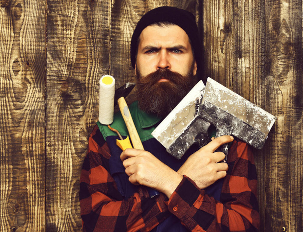 bearded painter man holding various building tools with serious face - Foto, Bild