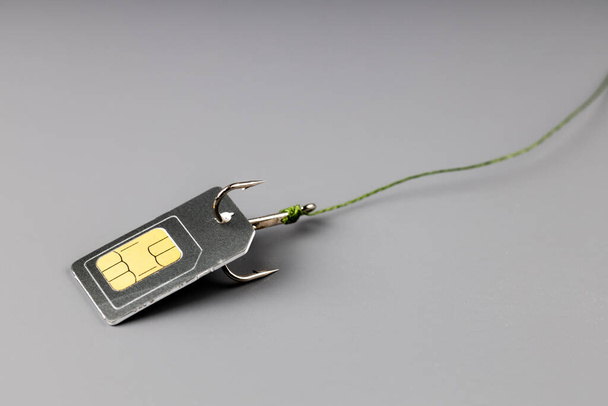 une carte SIM sur un crochet de pêche auquel le fil est attaché. attraper les abonnés et les braconner - Photo, image