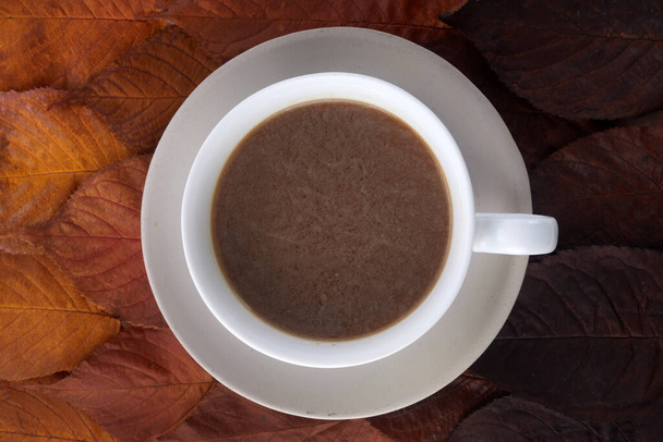 Cup of coffee with autumn leaves. Autumn decor, fall mood - 写真・画像