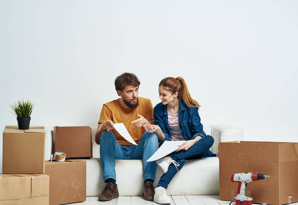 Man and woman are sitting on sofa with boxes of tools moving interior - Photo, Image