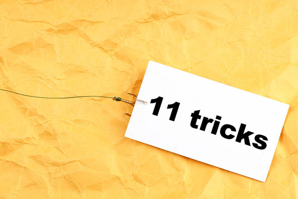 бумага на рыбном крючке с 11 трюками, написанными на ней. треки для людей - Фото, изображение