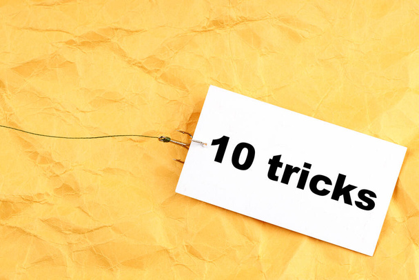 papel em um gancho de pesca com 10 truques escritos nele. truques para as pessoas - Foto, Imagem