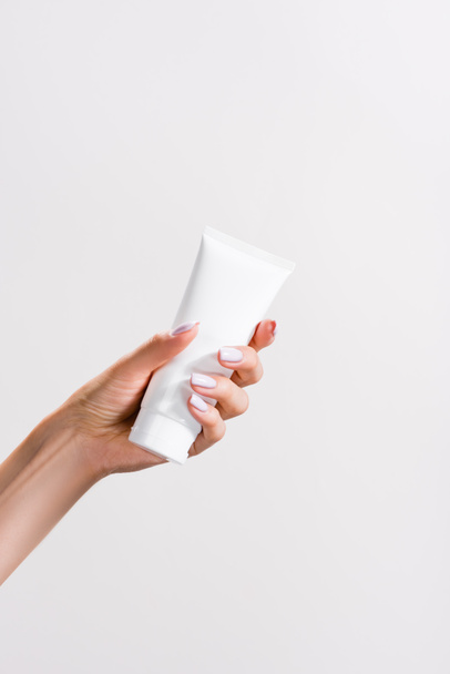 cropped view of woman holding tube of hand cream isolated on grey - Foto, Bild