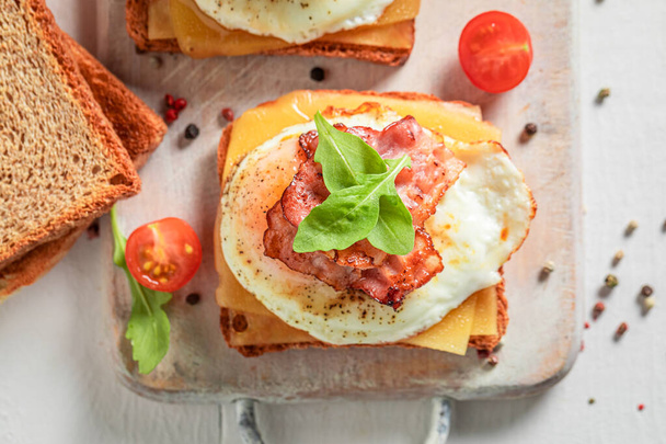 Crunchy toast with egg, cheese and bacon on white board - Photo, Image