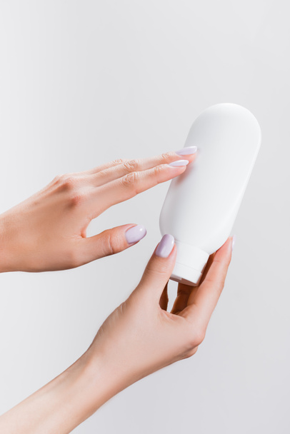 cropped view of woman holding tube of hand lotion isolated on grey - Foto, Bild