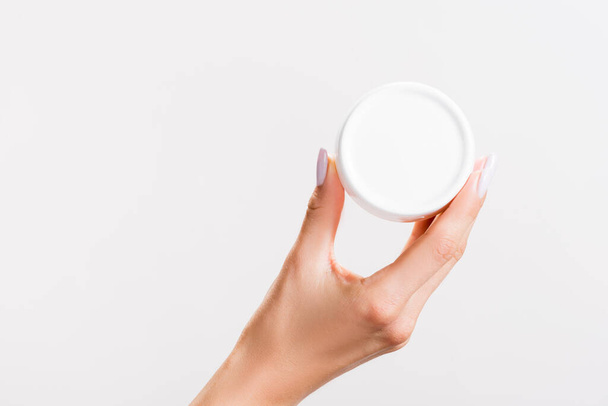 cropped view of woman holding container of hand cream isolated on grey - Foto, Bild
