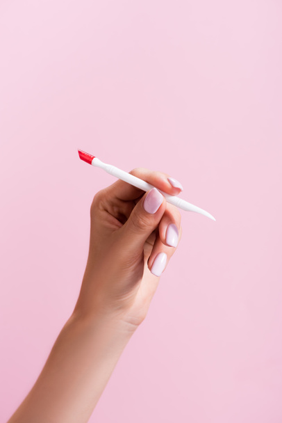 bijgesneden weergave van vrouw met nagelriemen pusher geïsoleerd op roze - Foto, afbeelding