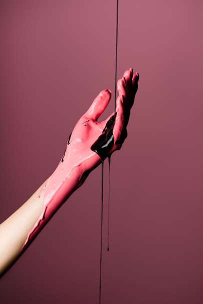 visão parcial da mão com tinta gotejante isolada sobre rosa - Foto, Imagem