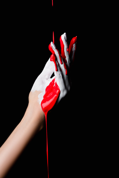 vista parcial de la mano pintada de blanco con pintura de goteo rojo aislado en negro - Foto, Imagen