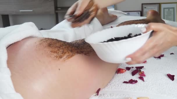 Kobieta masażysta ręce stosuje maskę czekoladową i masaże pośladki zrelaksowany kobieta - Materiał filmowy, wideo