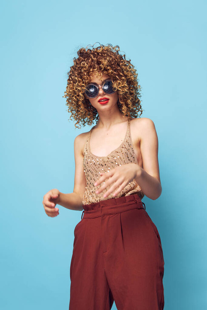 Портрет женщины вьющиеся волосы красные губы модная одежда студии солнцезащитные очки  - Фото, изображение
