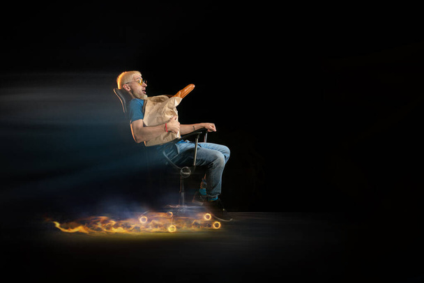 Fast delivery service - deliveryman on chair driving with order in fire on dark background - Foto, immagini