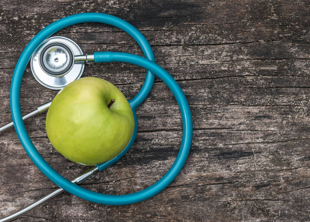 Concetto di giornata mondiale della salute con mela nutriente naturale verde con stetoscopio del medico a forma di amore cardiaco - Foto, immagini
