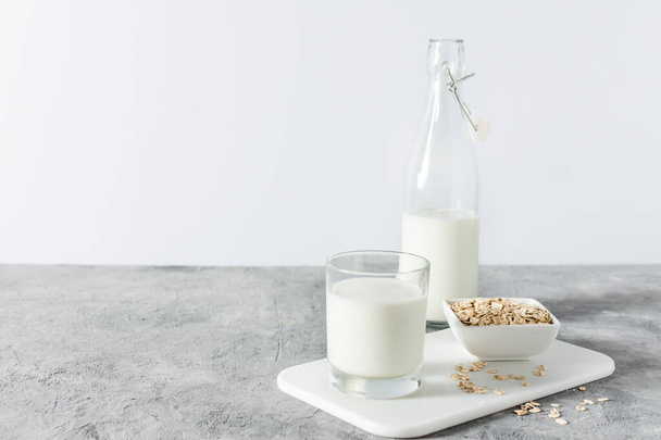 Homemade non dairy alternative milk made from oat flakes. Vegan oat milk on grey concrete table. - Foto, imagen