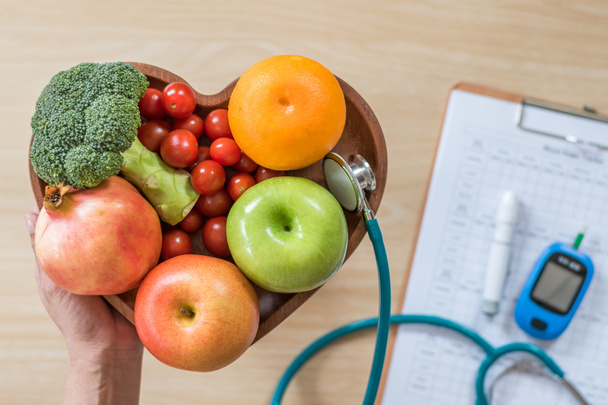 Monitor cukrzycy, dieta Cholesterol i zdrowa żywność jedzenie koncepcja żywieniowa z czystych owoców w naczyniu dietetycznym serca i pacjenta kontroli stężenia cukru we krwi rekord z zestawu narzędzi do pomiaru cukrzycy - Zdjęcie, obraz