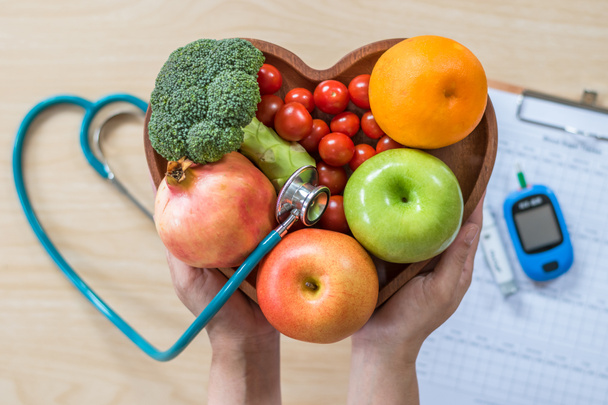 Cukorbetegség-monitor, koleszterin diéta és egészséges táplálkozás táplálkozás táplálkozási koncepció tiszta gyümölcsökkel a táplálkozási szakember szívételében és a beteg vércukorszint-szabályozó készletével - Fotó, kép