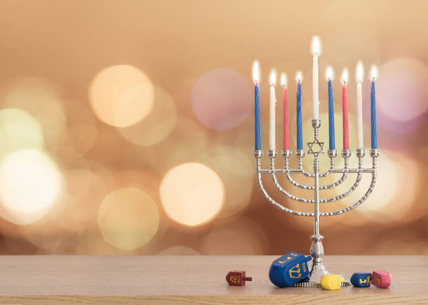 Hanukkah sfondo festa ebraica con menorah (candelabro giudaismo) Festival delle Luci e Festa della Dedicazione con candele accese, gioco tradizionale Dreidrel giocattolo sul tavolo di legno e sul bagliore sole autunno bokeh - Foto, immagini