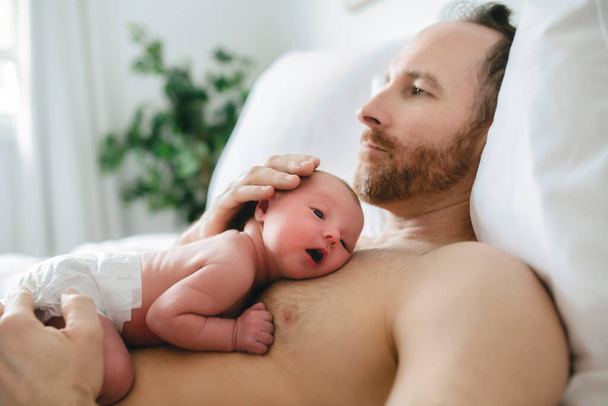 A father with a newborn baby in bed - Φωτογραφία, εικόνα