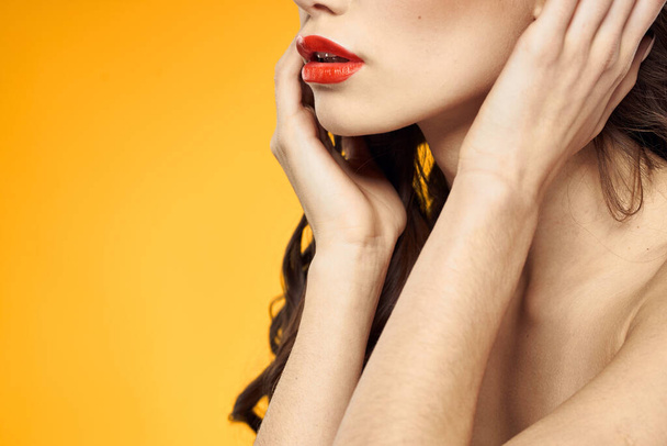 hermosa morena labios rojos hombros desnudos cuidado de la piel fondo amarillo - Foto, imagen