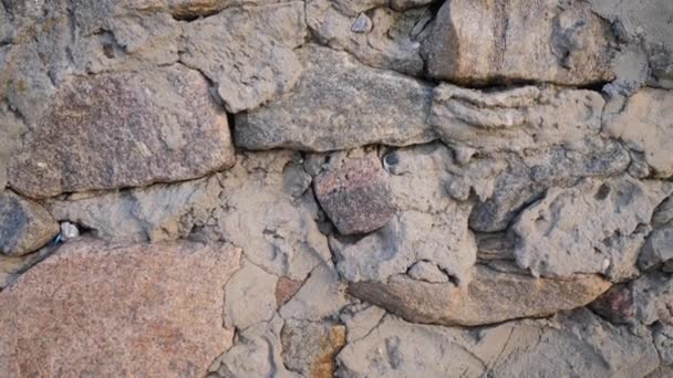 Textúra régi kövek különböző formájú varratok. Zárjuk le a kopott falazatot. Kőfal egyenetlen különböző ősi romlandó macskakövekből - Felvétel, videó