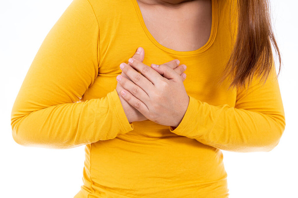 Nainen koskettaa sydäntään tai rintaansa eristetty valkoinen tausta. Terveydenhuollon lääketieteellisen tai jokapäiväisen elämän käsite. - Valokuva, kuva
