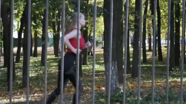 corridore caucasico della ragazza di idoneità in abbigliamento sportivo che funziona al parco di autunno il giorno soleggiato - Filmati, video