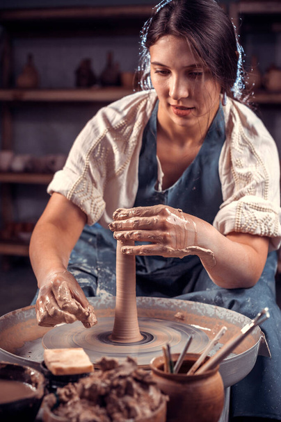 Stylowy profesjonalny garncarz demonstruje proces produkcji naczyń ceramicznych przy użyciu starej technologii. Pojęcie kobiety w wolnym strzelcu, biznesu, hobby. - Zdjęcie, obraz