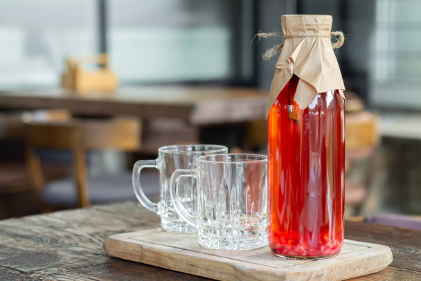 Kombucha thee met bessen in glazen fles naast glazen bekers. Gezonde gegiste drank - Foto, afbeelding