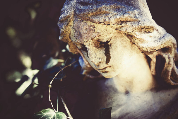 Morte. Frammento di antica statua di angelo piangente con lacrime in faccia come simbolo della fine della vita umana. Da vicino.. - Foto, immagini