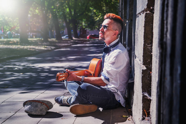 Straatmuziek kunst. Portret van een jonge man die buiten gitaar speelt in de oude Europese stad. - Foto, afbeelding