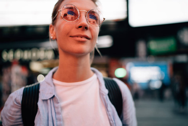 Happy young female traveler in glasses standing on street of New York and looking away while enjoying spending time in USA - Fotoğraf, Görsel