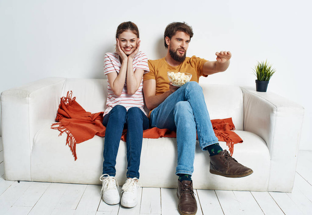 mies ja nainen sohvalla katsomassa televisiota valoisassa huoneessa - Valokuva, kuva