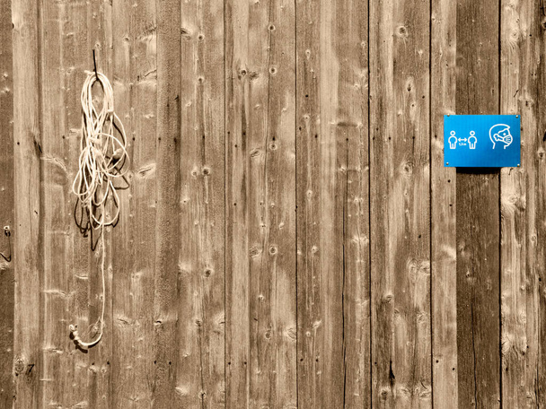 Повний вигляд вивітрюваної дошки стіни великої рогатої худоби з мотузкою, прикріпленою до нігтя і синьою піктограмою; тоновані в Сефії.. - Фото, зображення