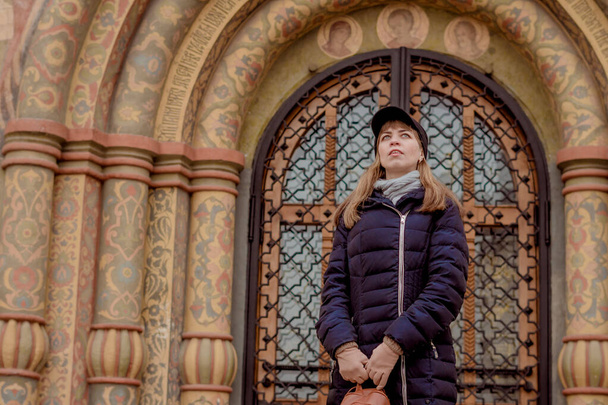 девушка стоит перед церковью с большими воротами с красивой картиной - Фото, изображение