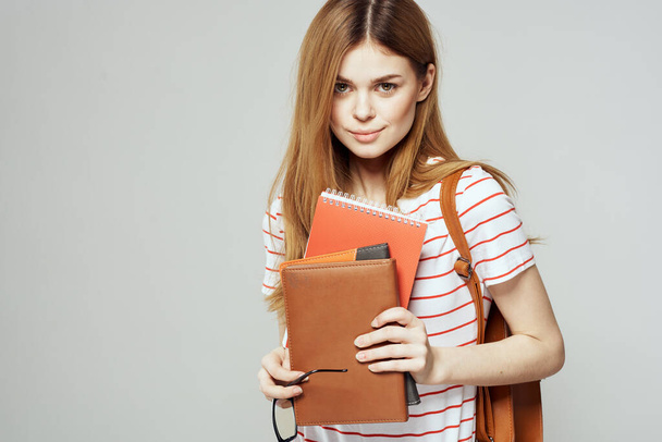 Studentessa con blocco note e occhiali su sfondo chiaro vista ritagliata di una T-shirt a righe - Foto, immagini