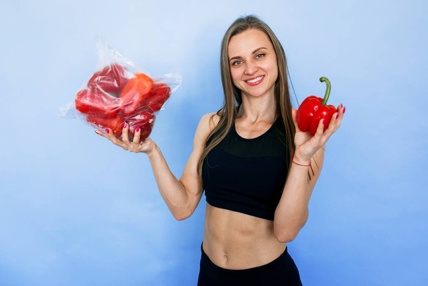 Een meisje met een Europees uiterlijk houdt een rode peper in haar handen. Bevroren groenten in een verpakking. - Foto, afbeelding