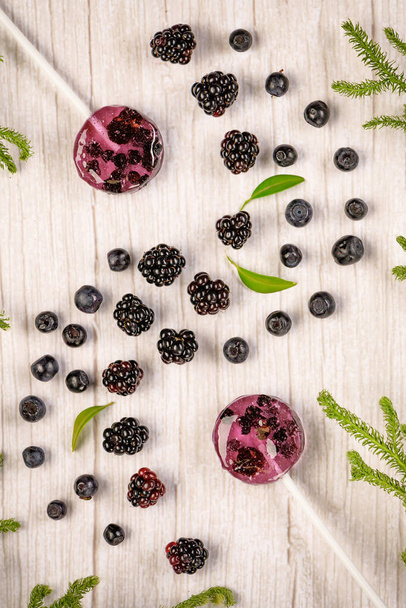 . Homemade lollipops made from natural dehydrated bilberry and blackberries on a white wooden background. Healthy vegan vegetarian food with no sweets. - Photo, Image