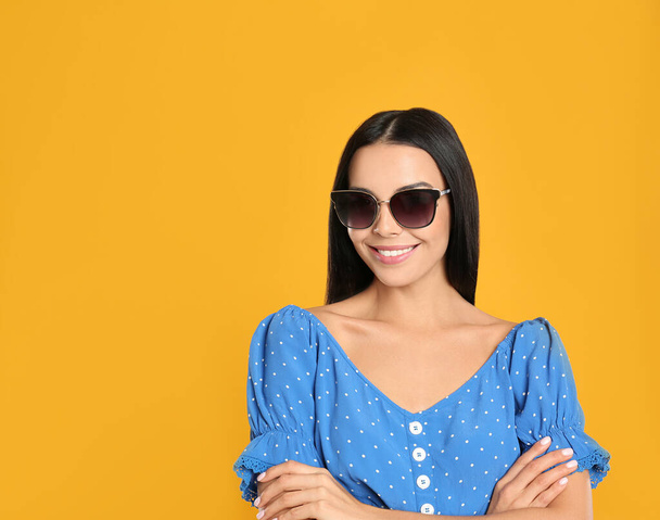Beautiful woman wearing sunglasses on yellow background. Space for text - Valokuva, kuva