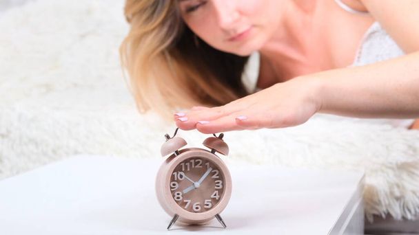 Woman in bed turns off the alarm clock in the morning. Close up alarm clock, selective focus. New day start concept, wake up early, daily routine - Photo, Image