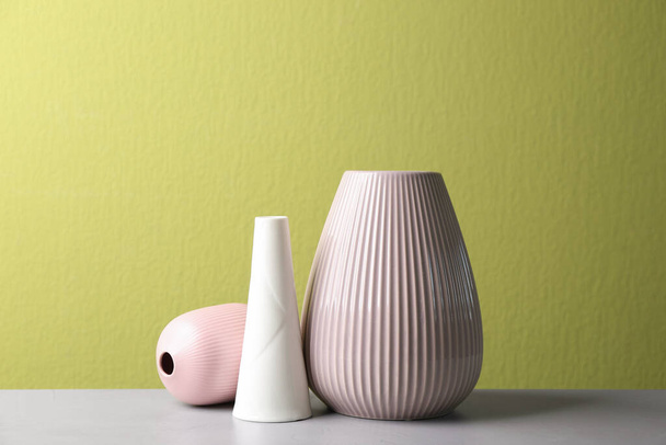 Stylish ceramic vases on grey stone table against green background - Valokuva, kuva
