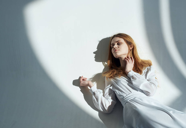 woman with red hair leaning against the north wall and a falling shadow Indoors - Photo, Image