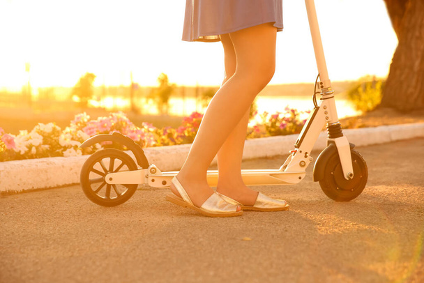 Woman riding electric kick scooter outdoors on sunny day, closeup - Фото, зображення