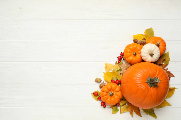 Flat lay composition with pumpkins and autumn leaves on white wooden table. Space for text - Photo, Image